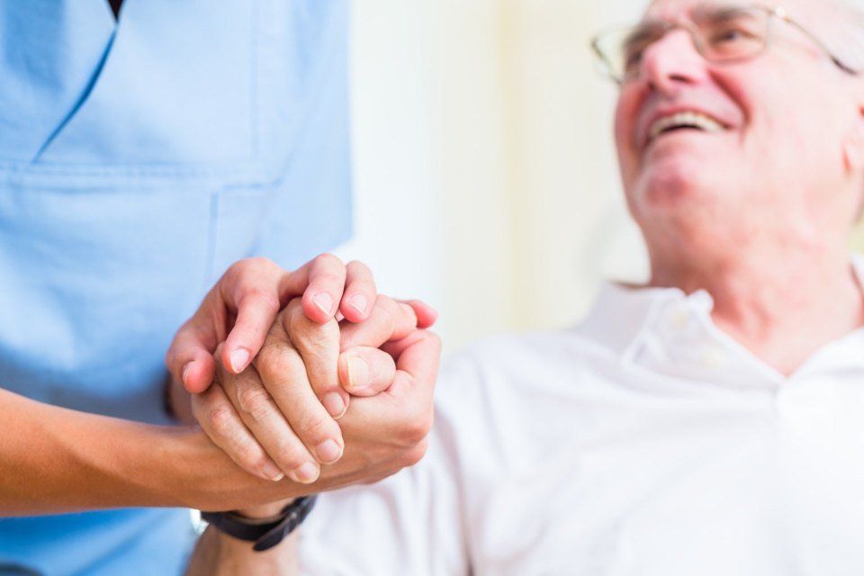 Person in scrubs holding an elderly mans hand