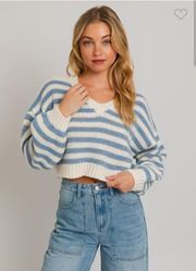 A woman is wearing a blue and white striped sweater and jeans.