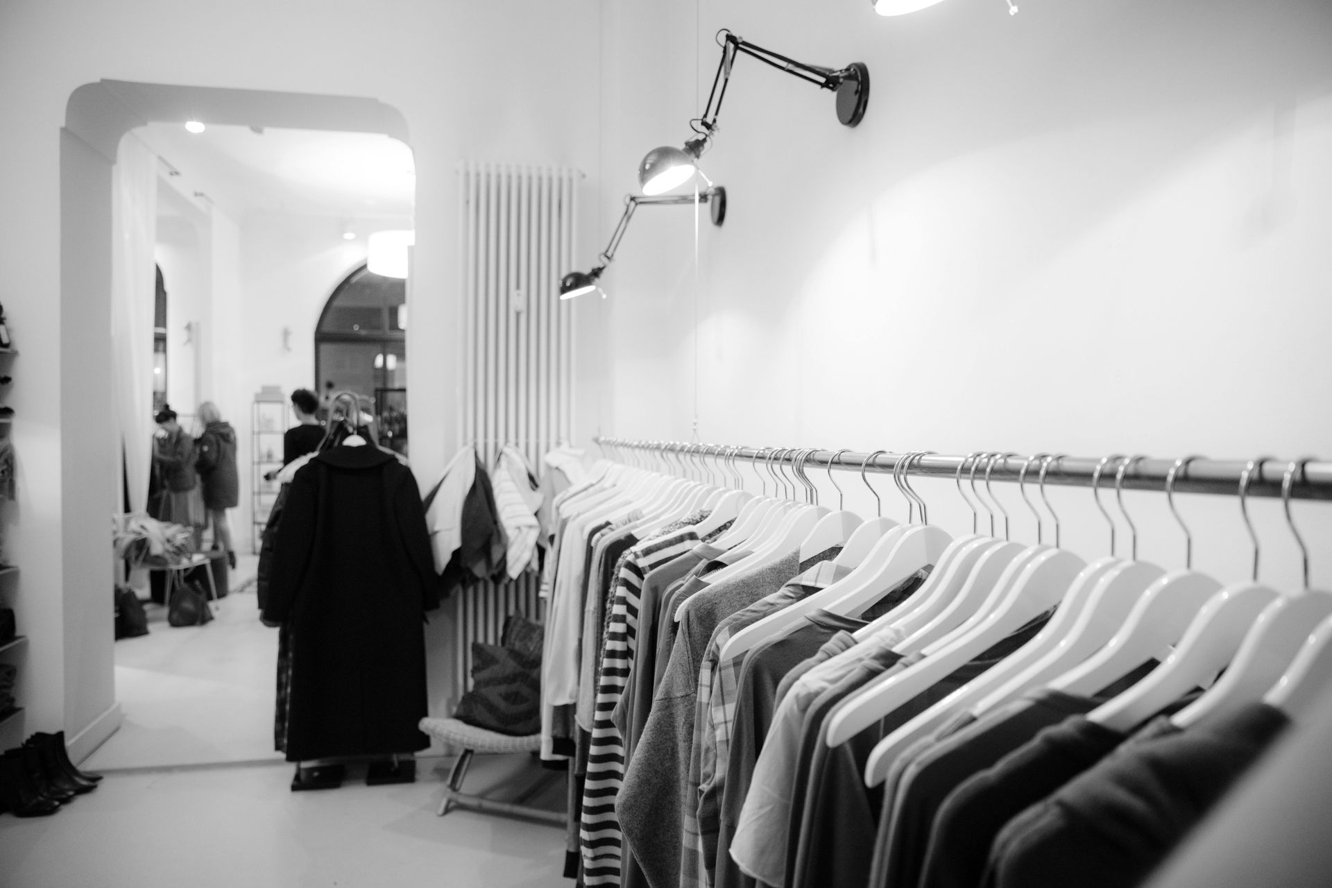 A black and white photo of a clothes rack in a store