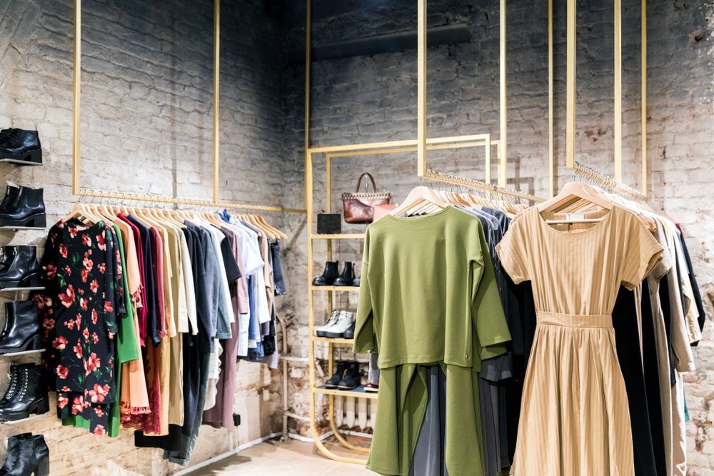 A clothes store with a lot of clothes hanging on racks.