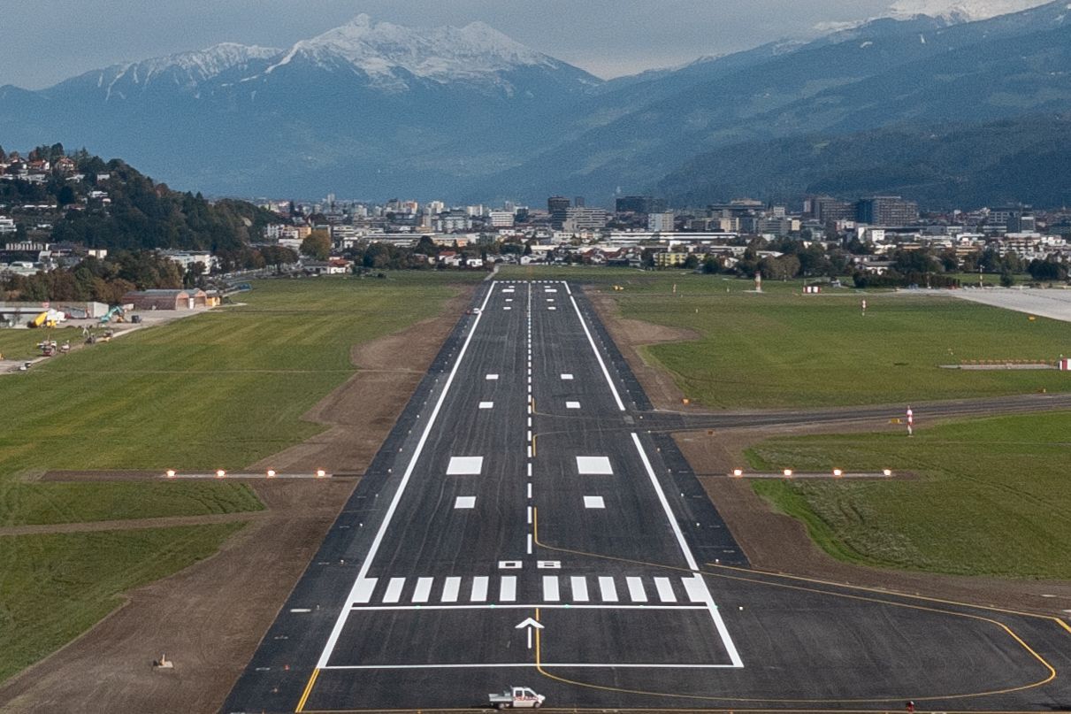 Eine Luftaufnahme einer Flughafenlandebahn mit Bergen im Hintergrund