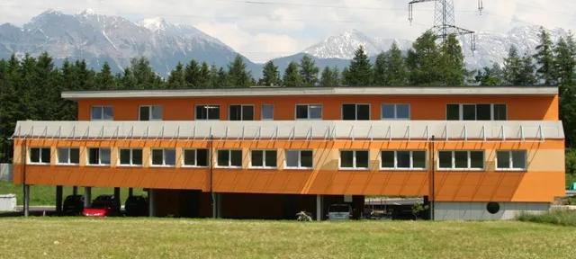 Ein großes orangefarbenes Gebäude mit Bergen im Hintergrund