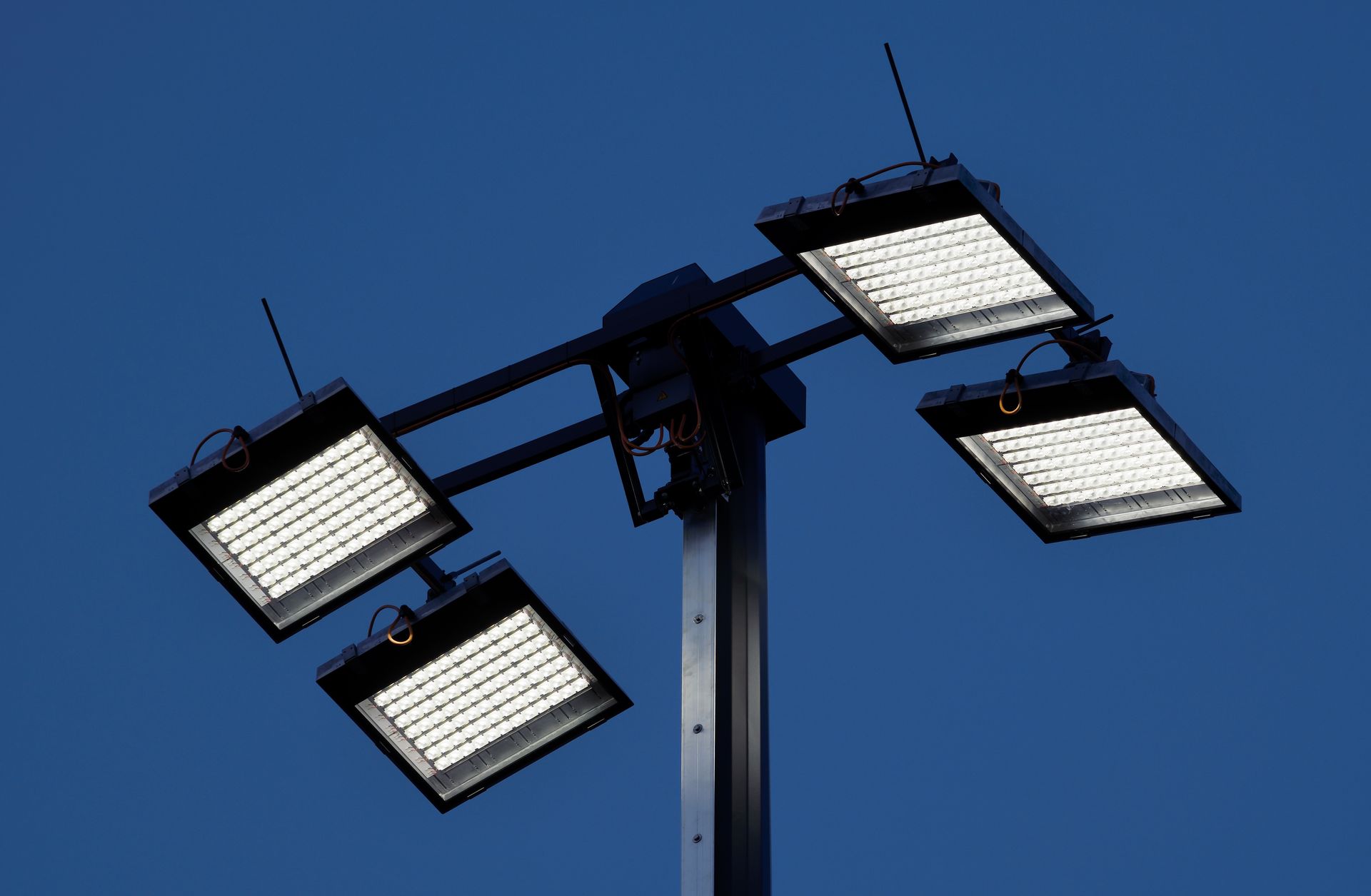 Ein Mast mit vier Lichtern vor einem blauen Himmel.