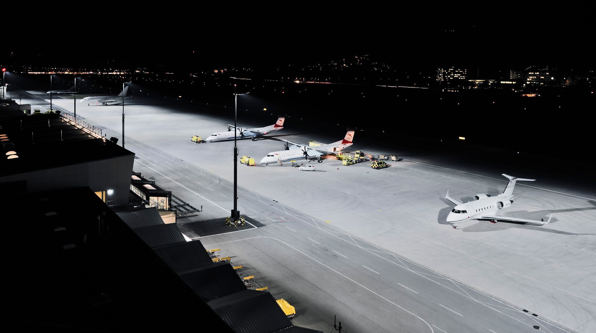 Mehrere Flugzeuge stehen nachts auf einer Landebahn