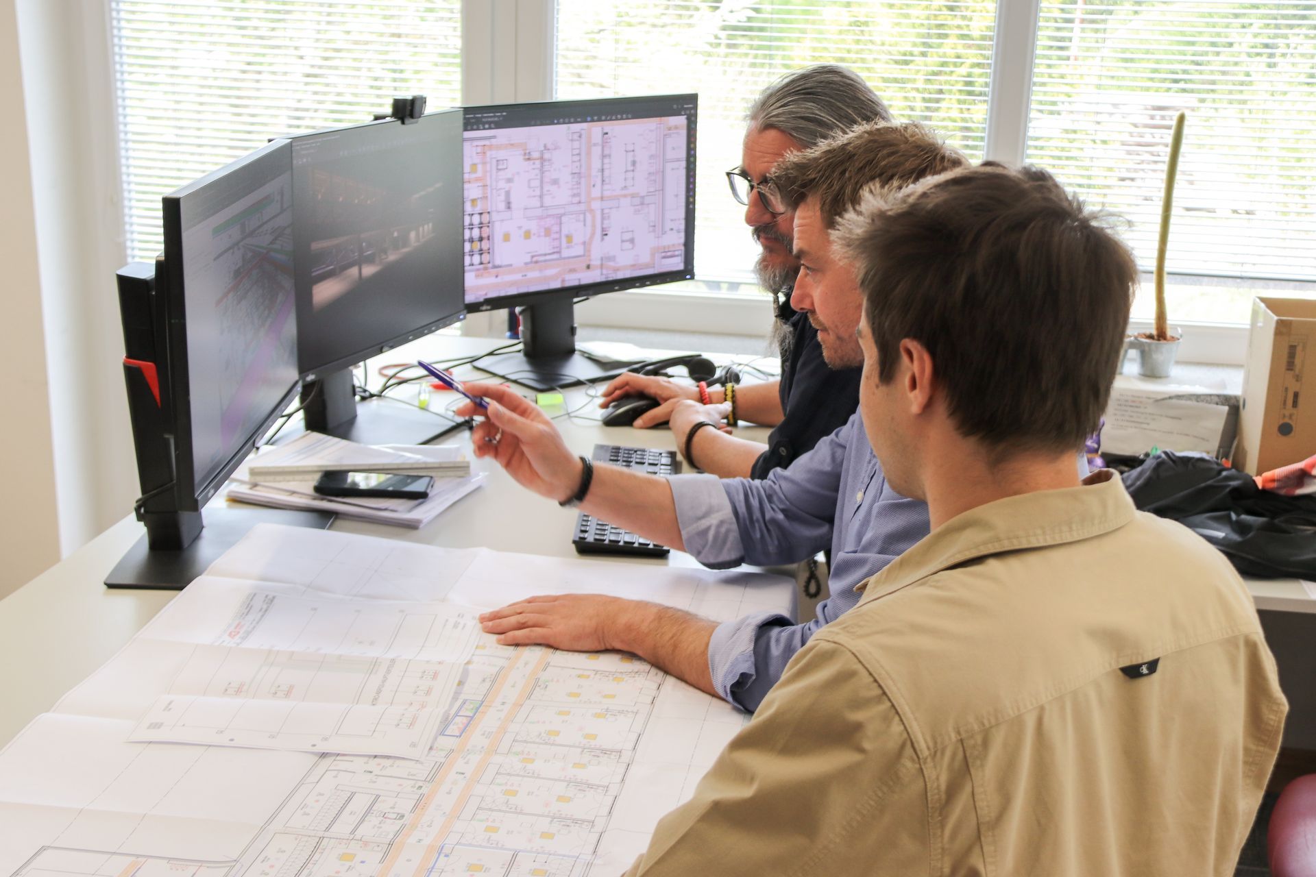 Eine Gruppe Männer sitzt an einem Schreibtisch und schaut auf einen Computerbildschirm.