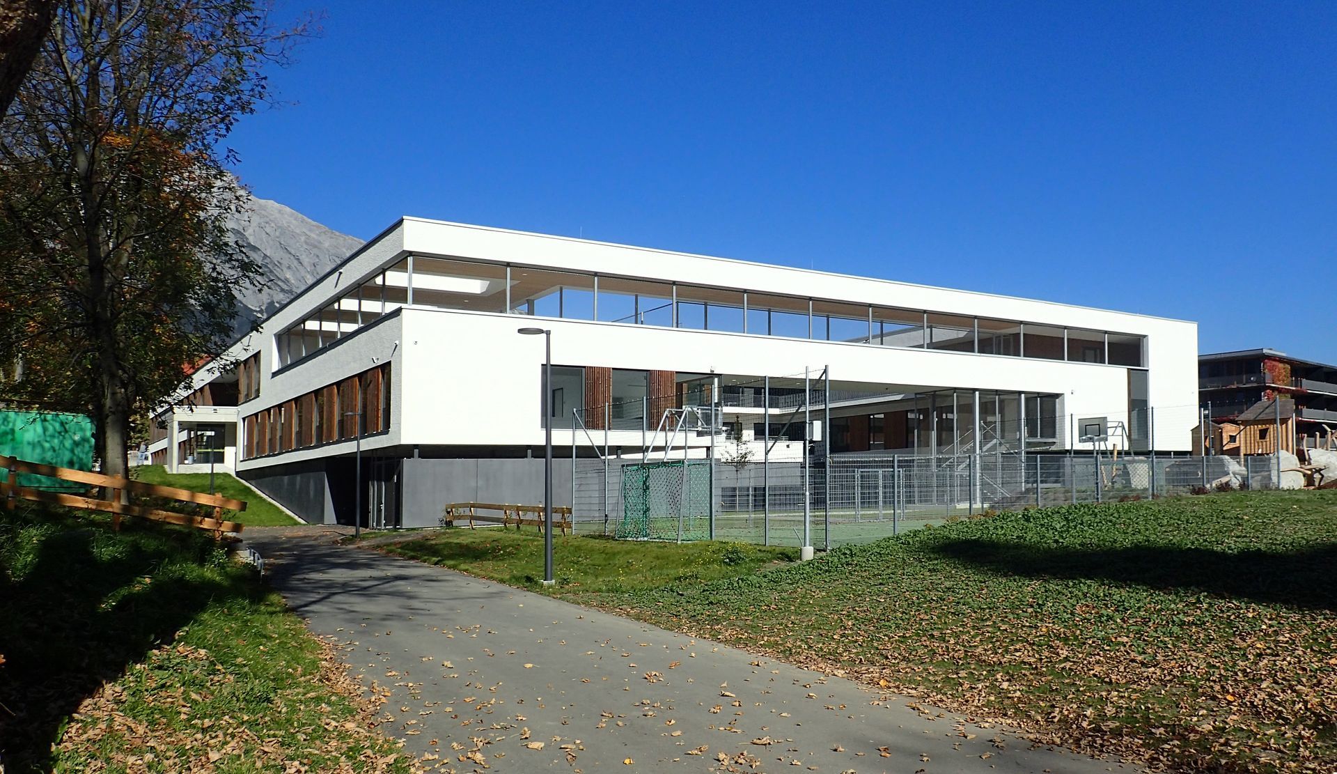 Ein großes weißes Gebäude mit einem Tennisplatz davor.