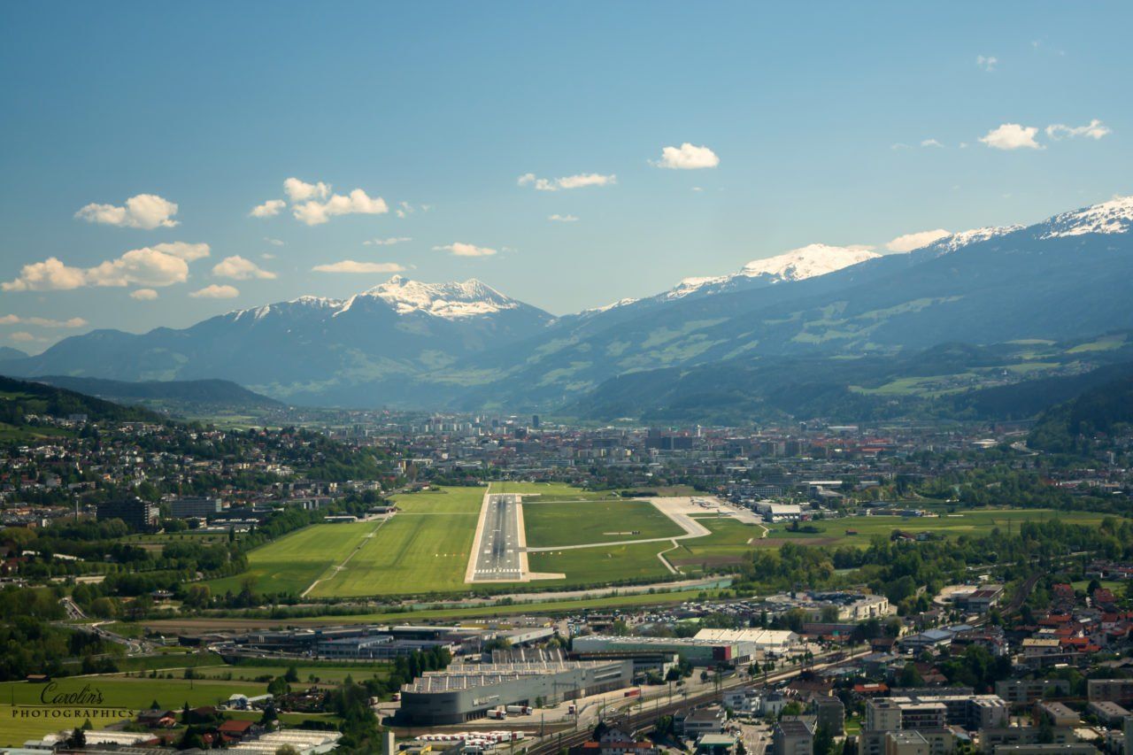 Eine Luftaufnahme einer Stadt und einer Landebahn mit Bergen im Hintergrund.