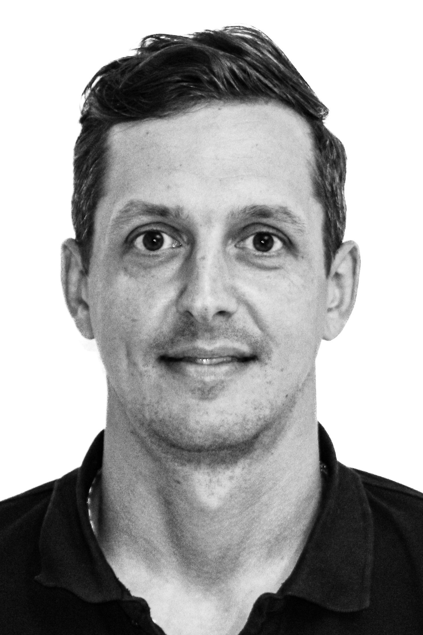 Ein Schwarzweißfoto eines Mannes, der eine Jacke und ein schwarzes Hemd trägt.