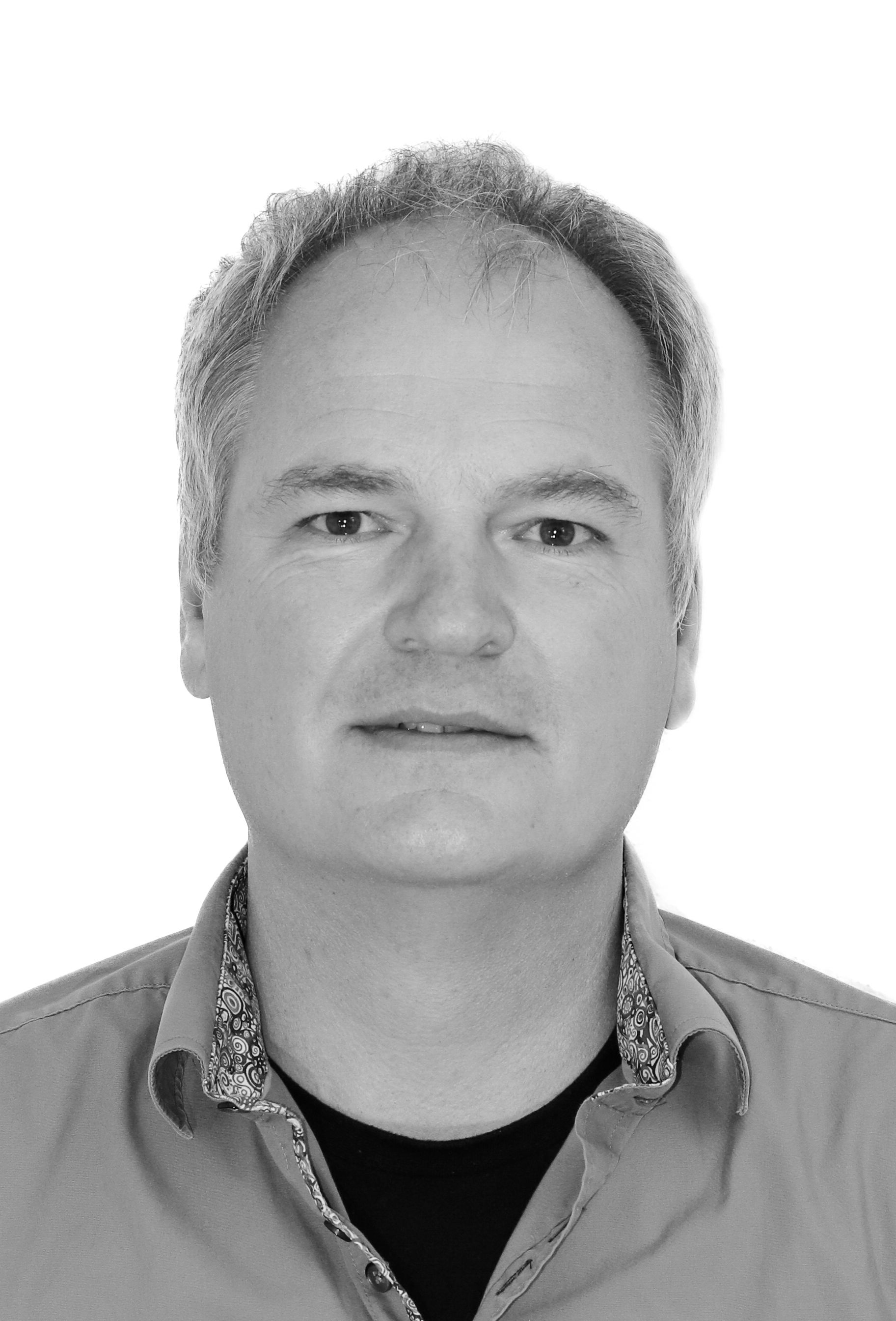 Ein Schwarzweißfoto eines Mannes, der ein Hemd und ein schwarzes T-Shirt trägt.