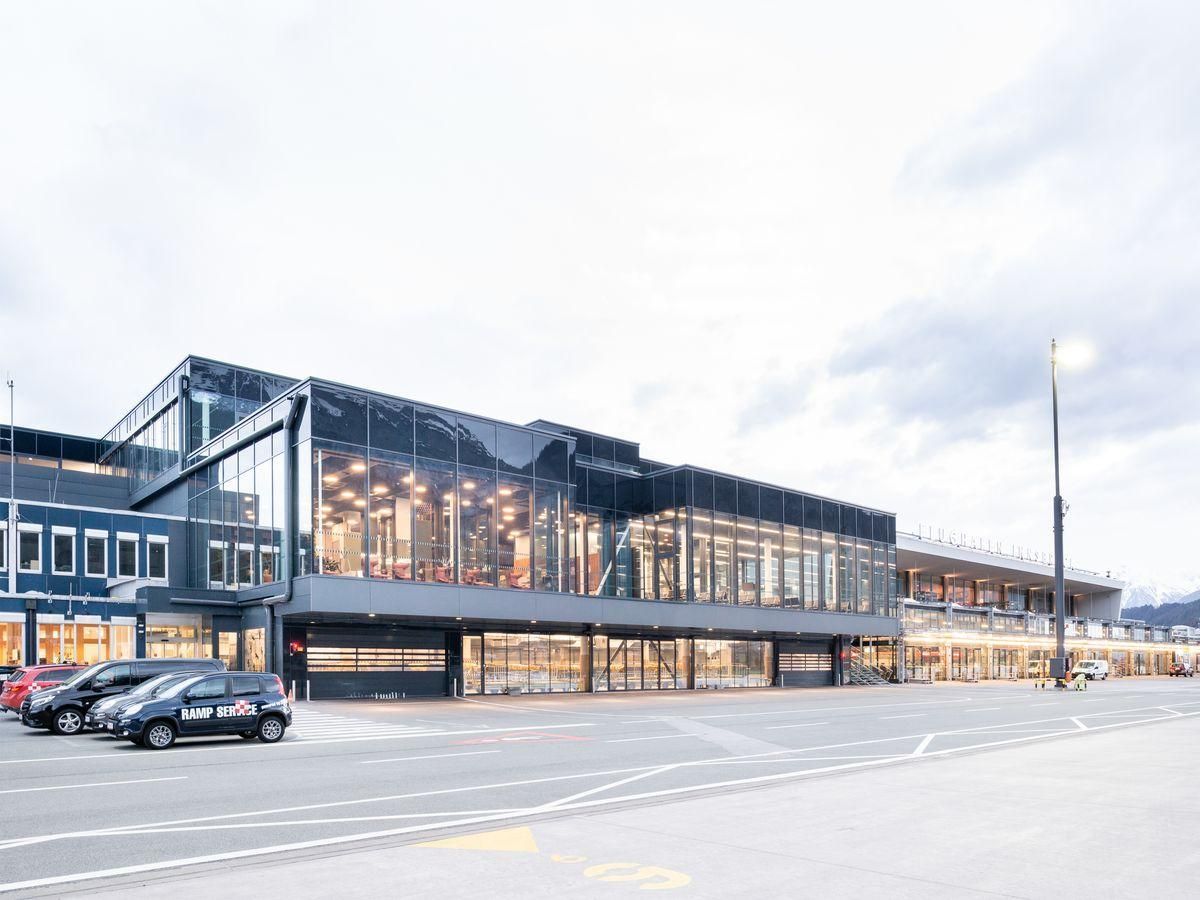 Ein großes Gebäude mit vielen Fenstern und davor geparkten Autos.