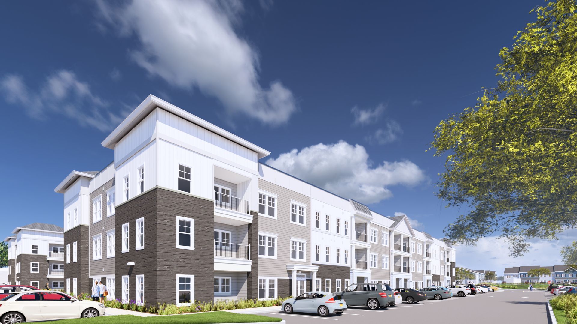 Modern apartment complex with gray and white exterior, parked cars, and a blue sky with clouds