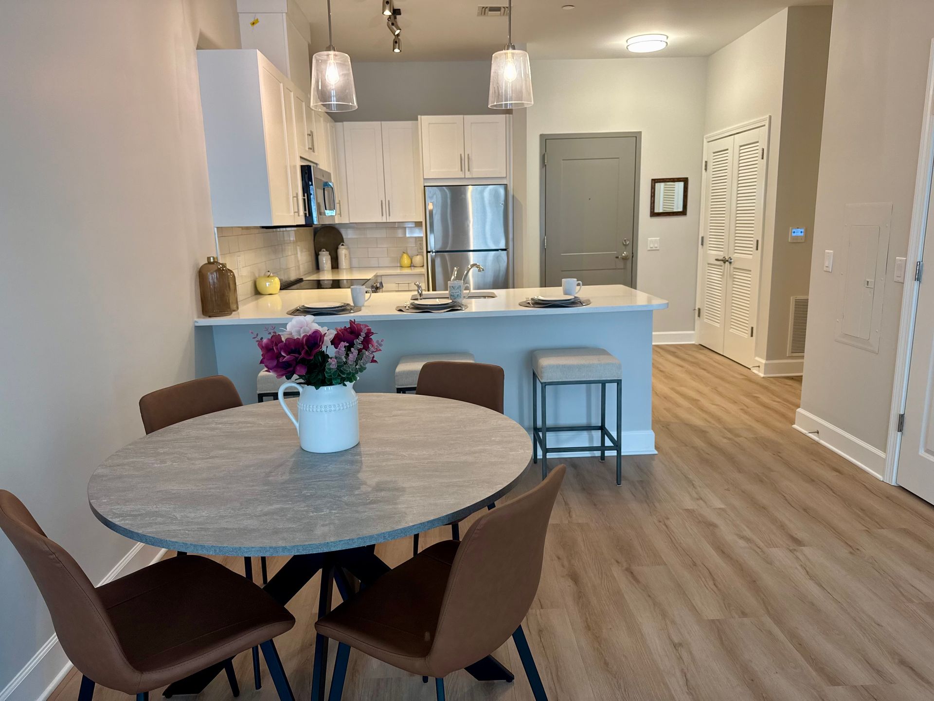 Modern kitchen and dining area with round table, pendant lights, and white cabinets