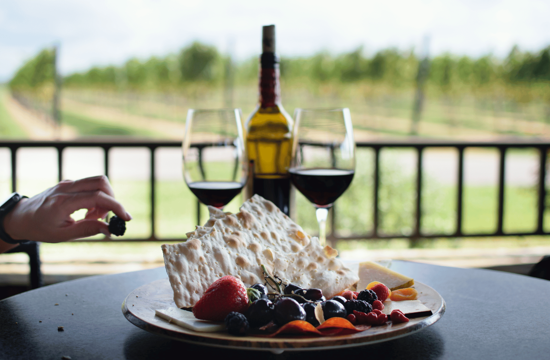 A plate of food with a bottle of wine and two glasses of wine on a table.