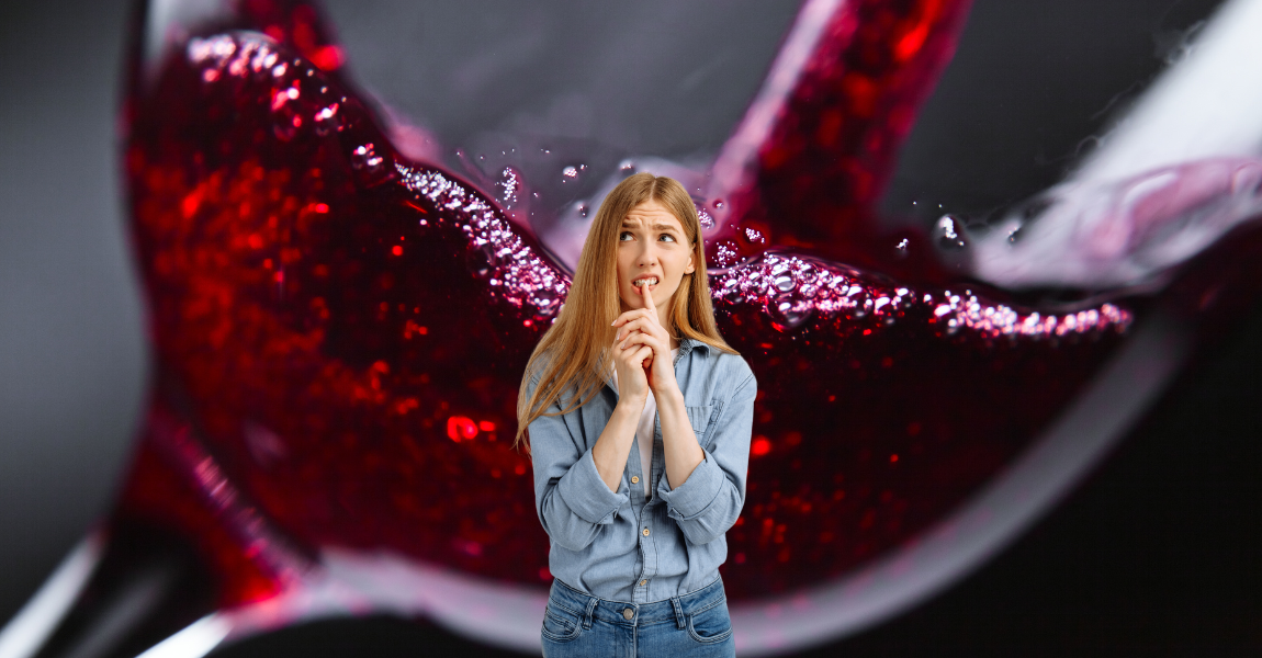 A woman is standing in front of a glass of red wine.