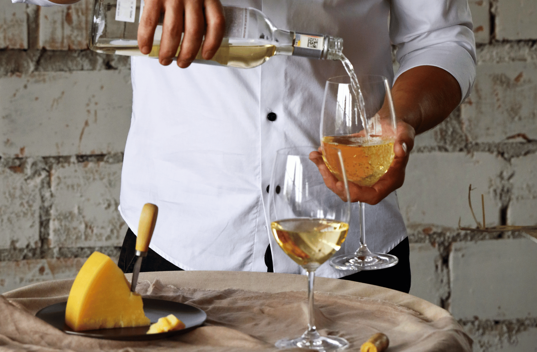 A man is pouring wine into a glass on a table.