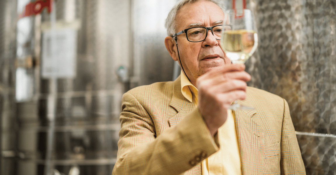 A man in a suit is holding a glass of wine.