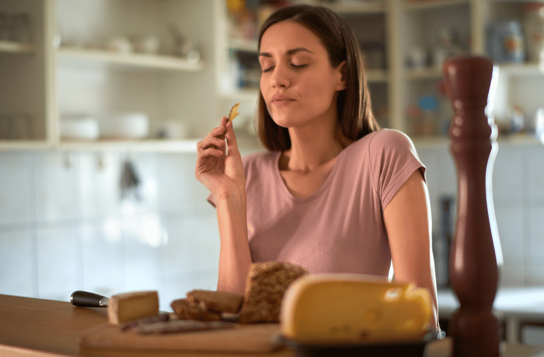 A woman is sitting at a table eating bread and cheese.