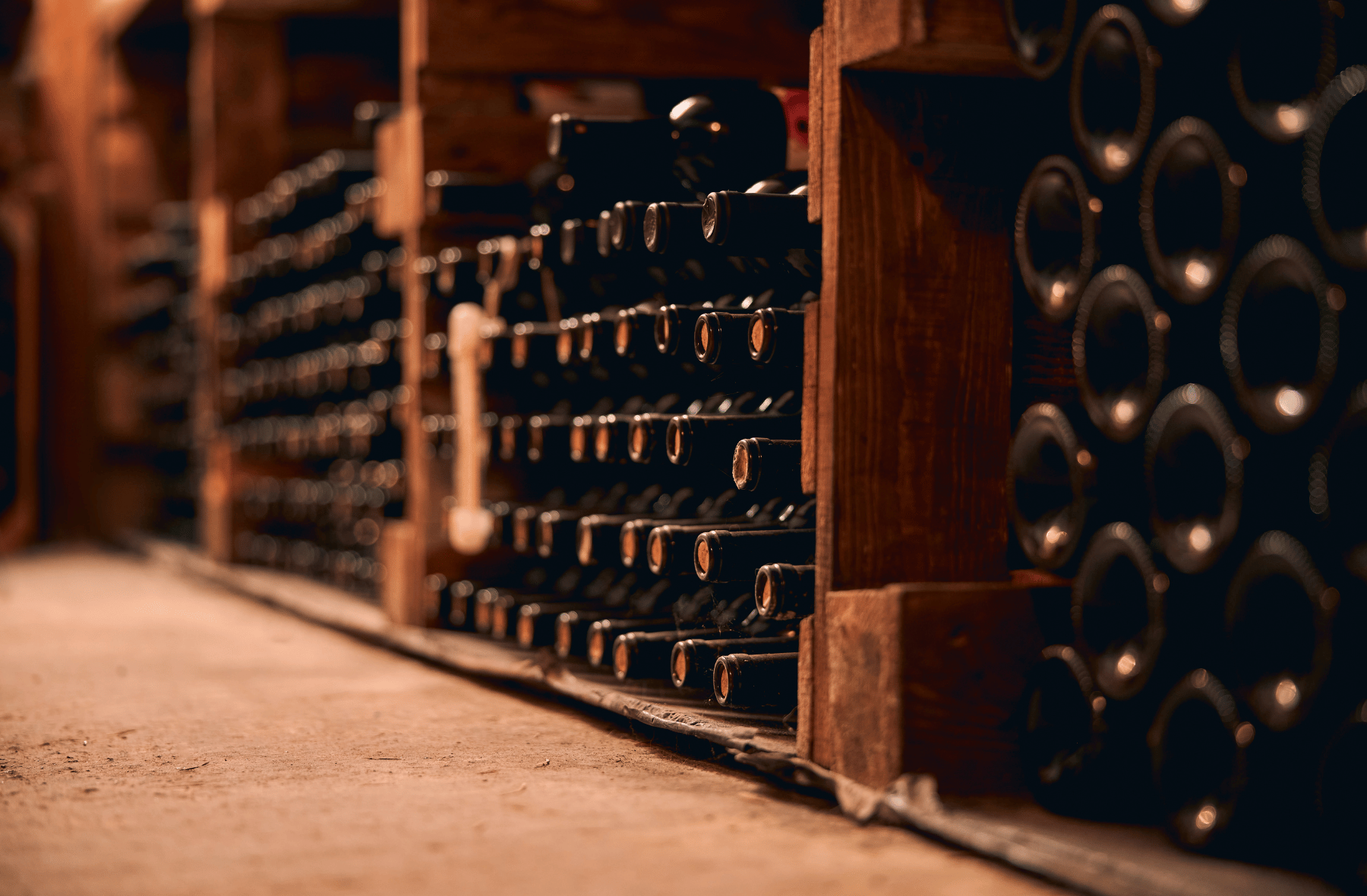 A row of wine bottles stacked on top of each other on wooden shelves in a wine cellar.