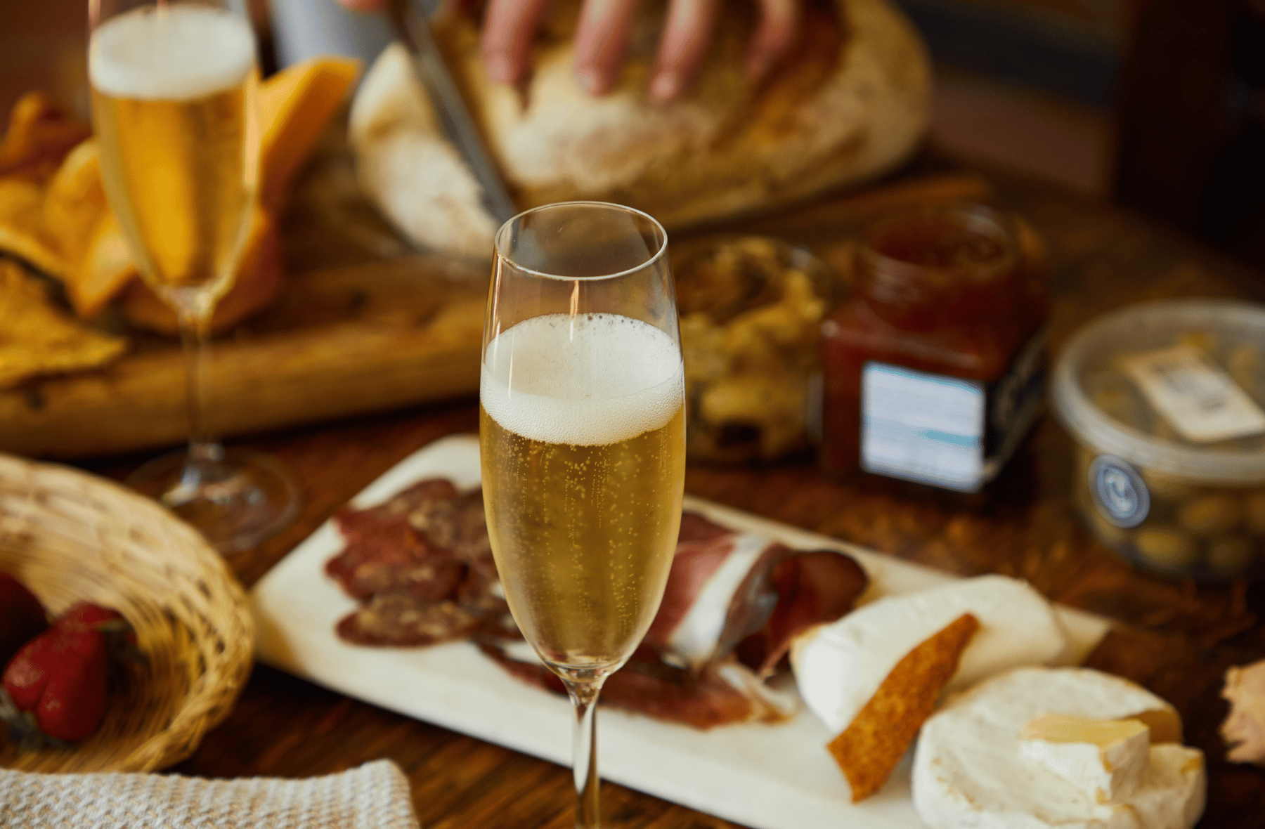 A glass of champagne is sitting on a table next to a plate of food.