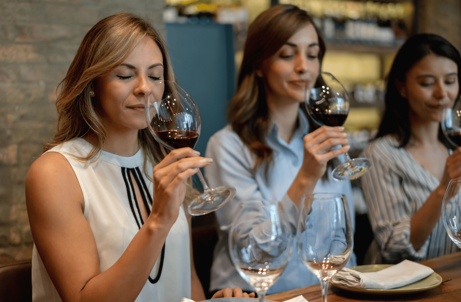 Three women are sitting at a table drinking wine.