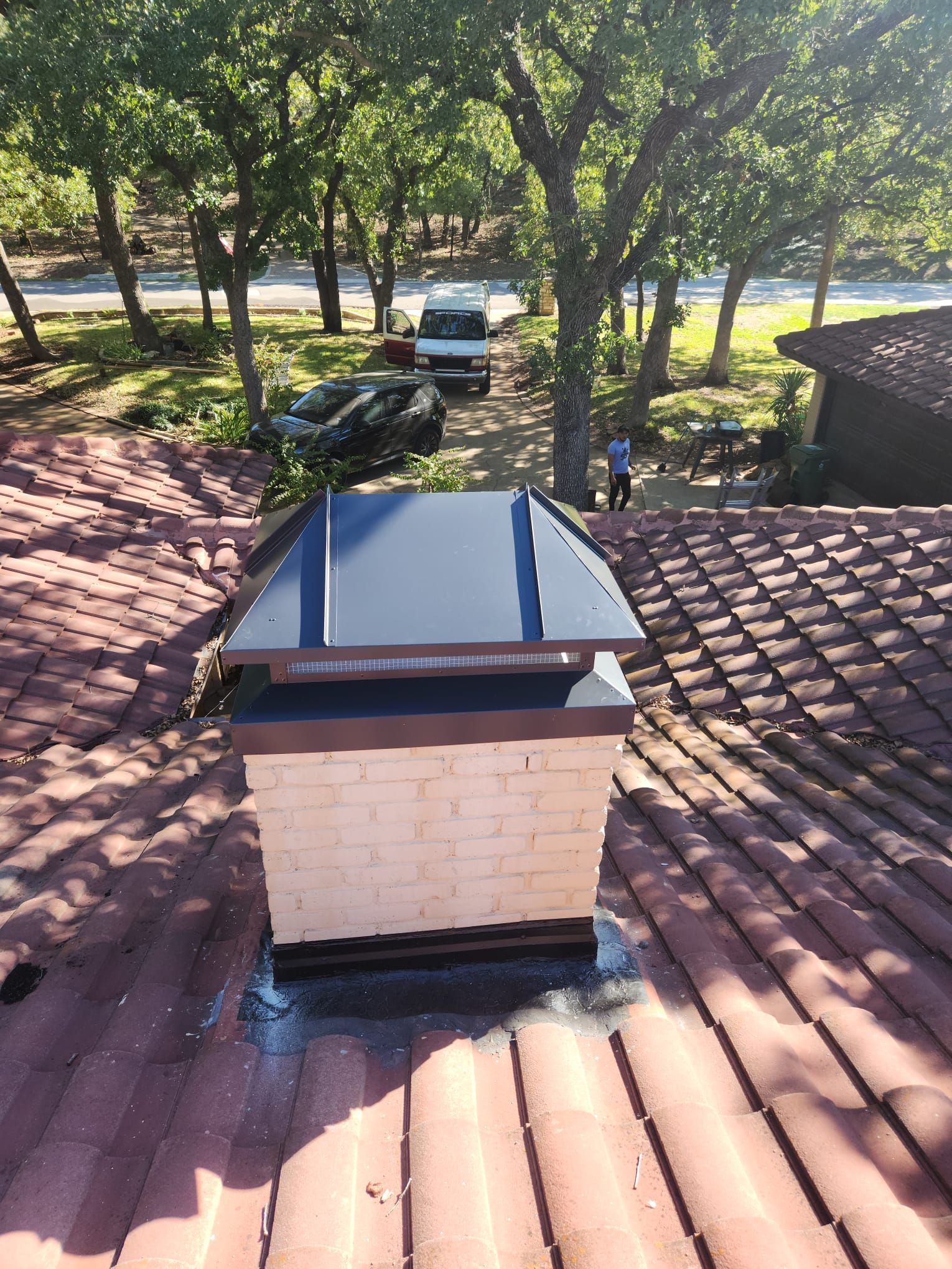 A chimney on top of a roof with trees in the background