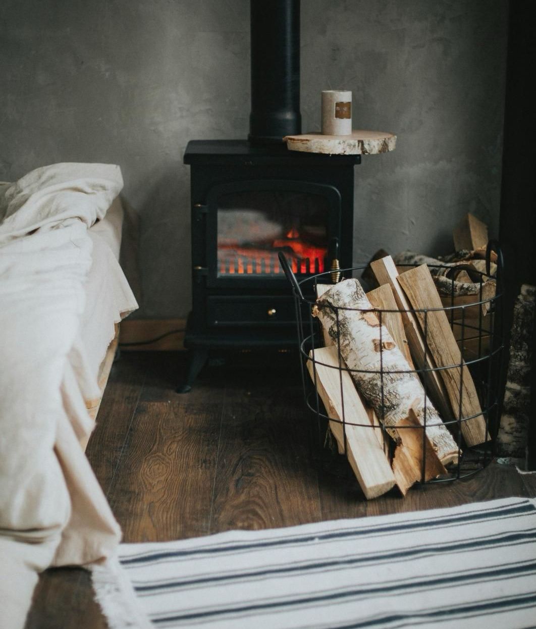 A fireplace with a basket of logs in front of it.