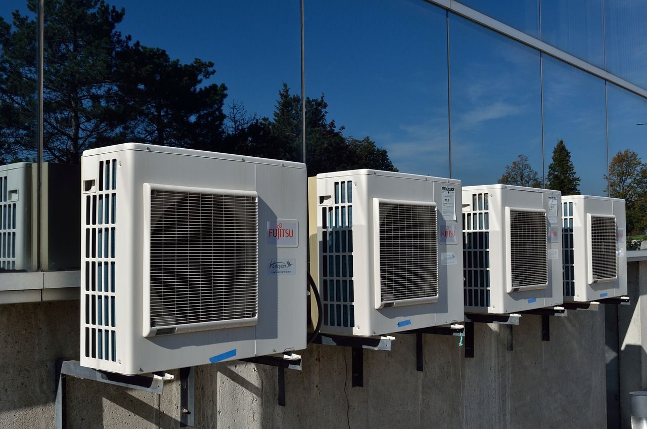 A row of air conditioners are lined up on a wall