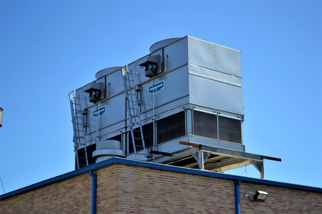 A large cooling tower is sitting on top of a brick building.