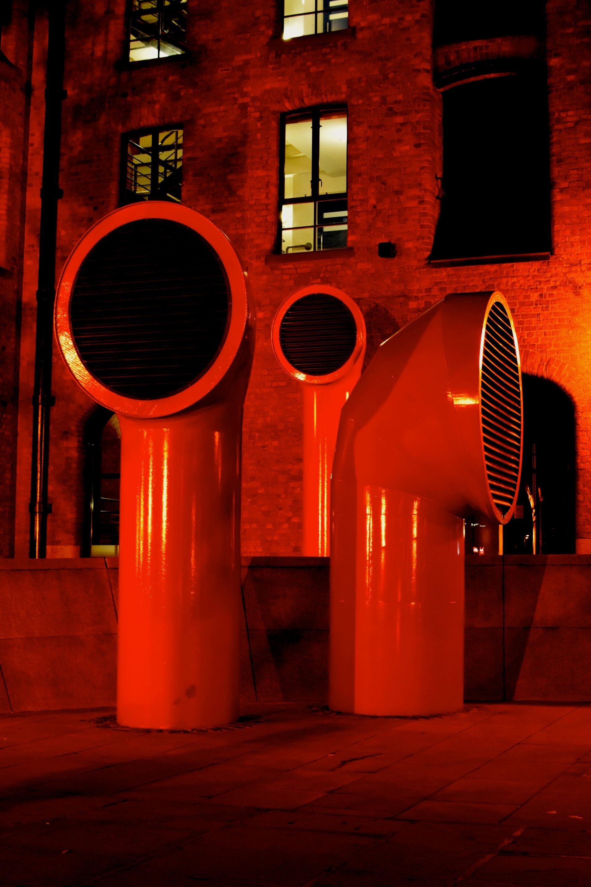 A row of orange pipes in front of a brick building