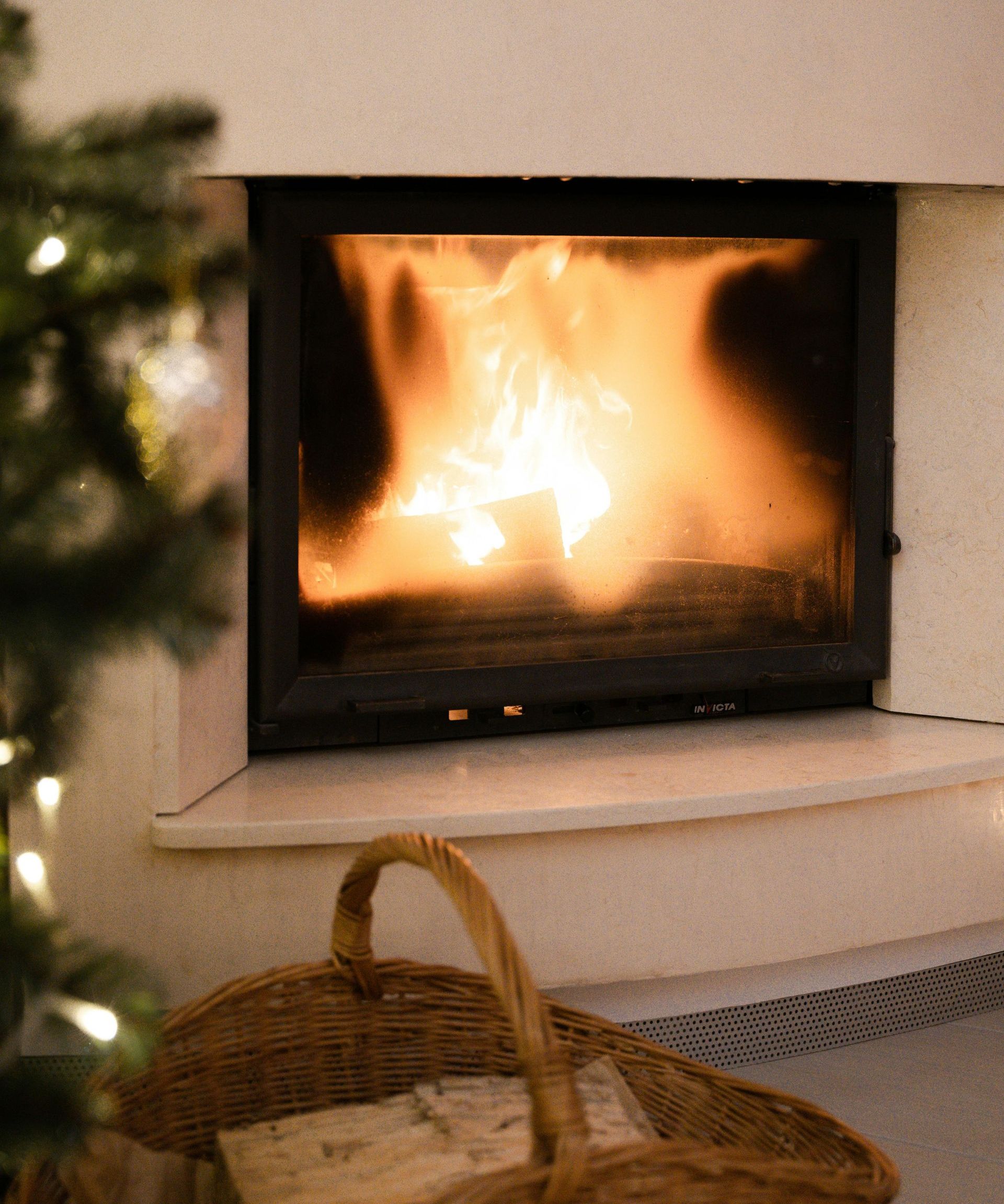 A fireplace with a basket of logs in front of it