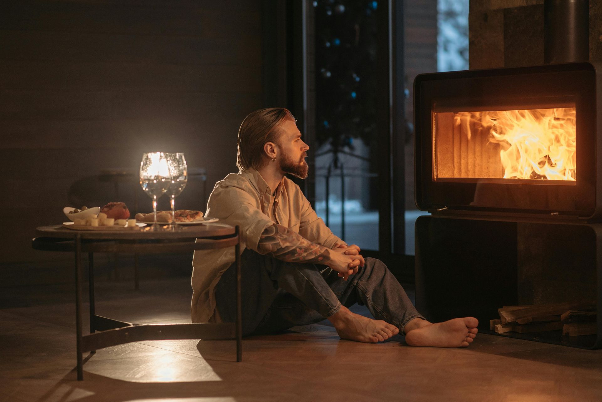 A man is sitting on the floor in front of a fireplace.