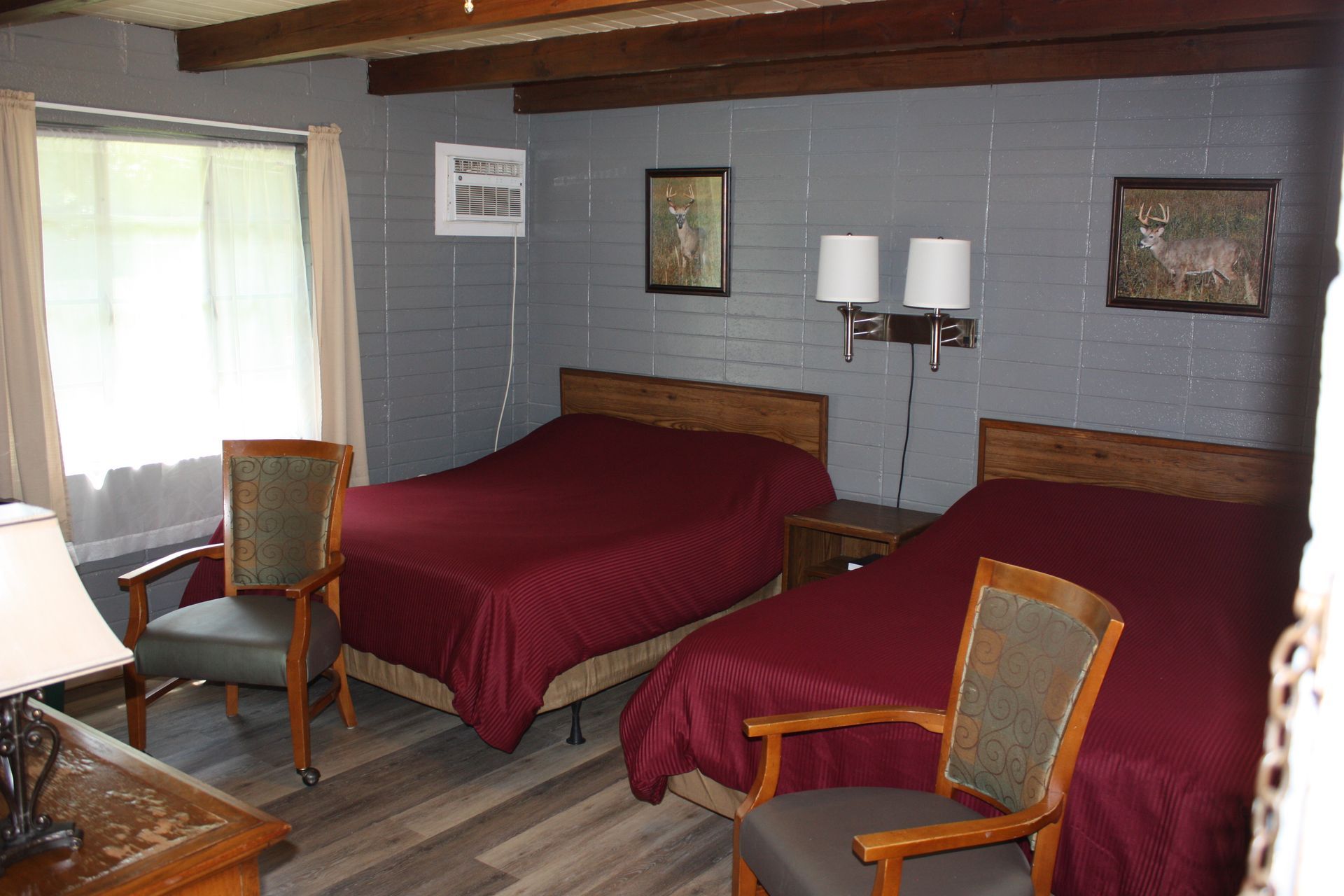 A hotel room with two beds and two chairs.