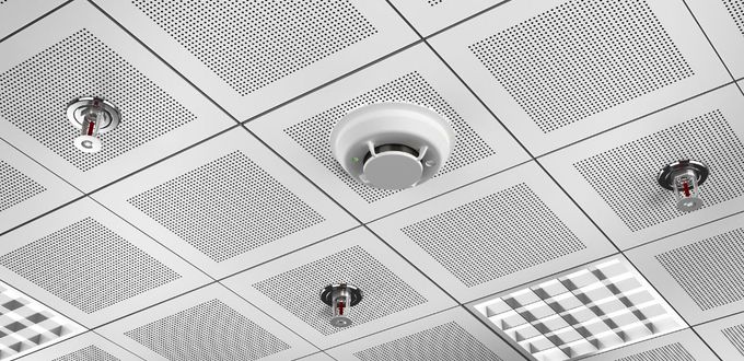 Ceiling with grid pattern, smoke detector, and fire sprinklers.
