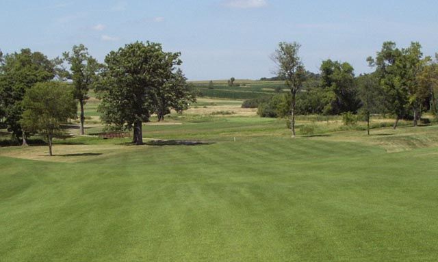A golf course with trees and grass on a sunny day