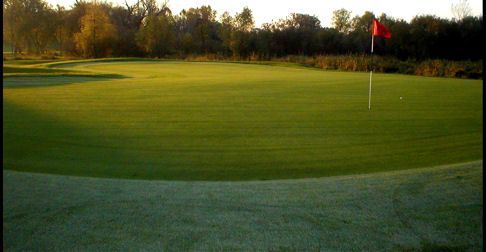 A golf course with a red flag on the green