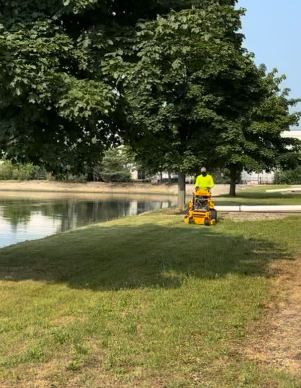 A person is riding a lawn mower on a lush green lawn.