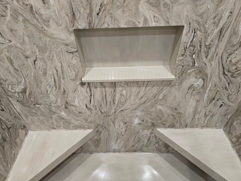 A bathroom with a marble wall and two shelves.