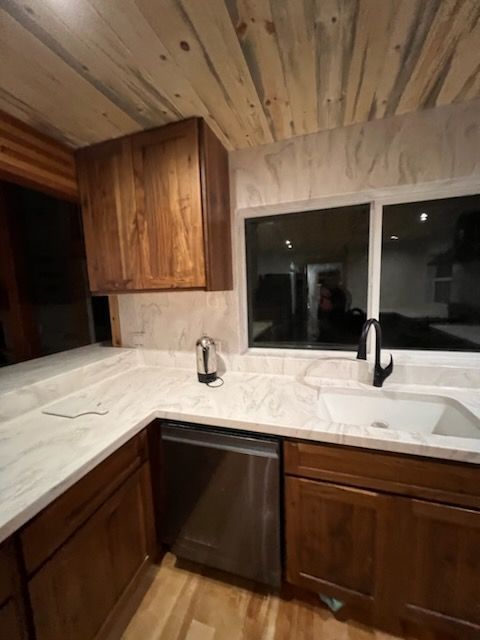 A kitchen with a sink , dishwasher , and wooden cabinets.