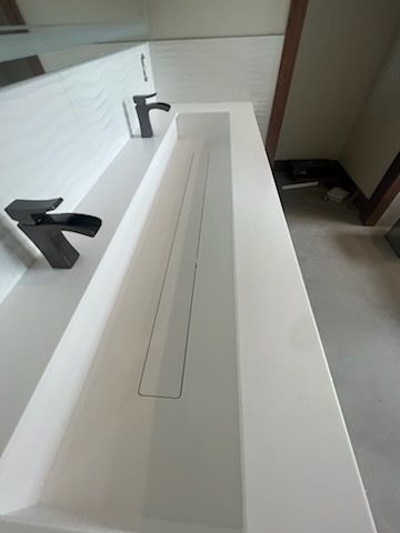 A bathroom sink with two black faucets and a mirror.