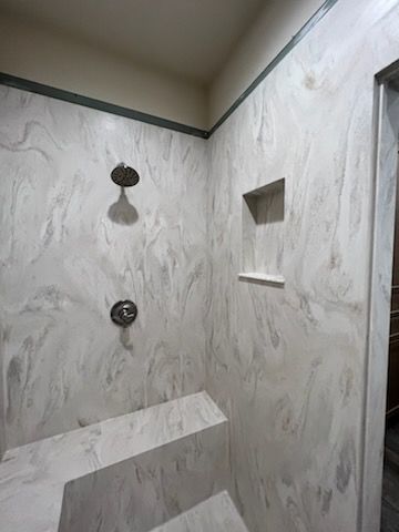 A shower with a bench and a shower head in a bathroom.