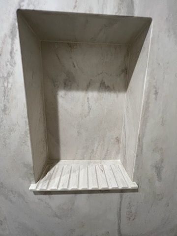 A shower niche in a bathroom with a soap dish in it.