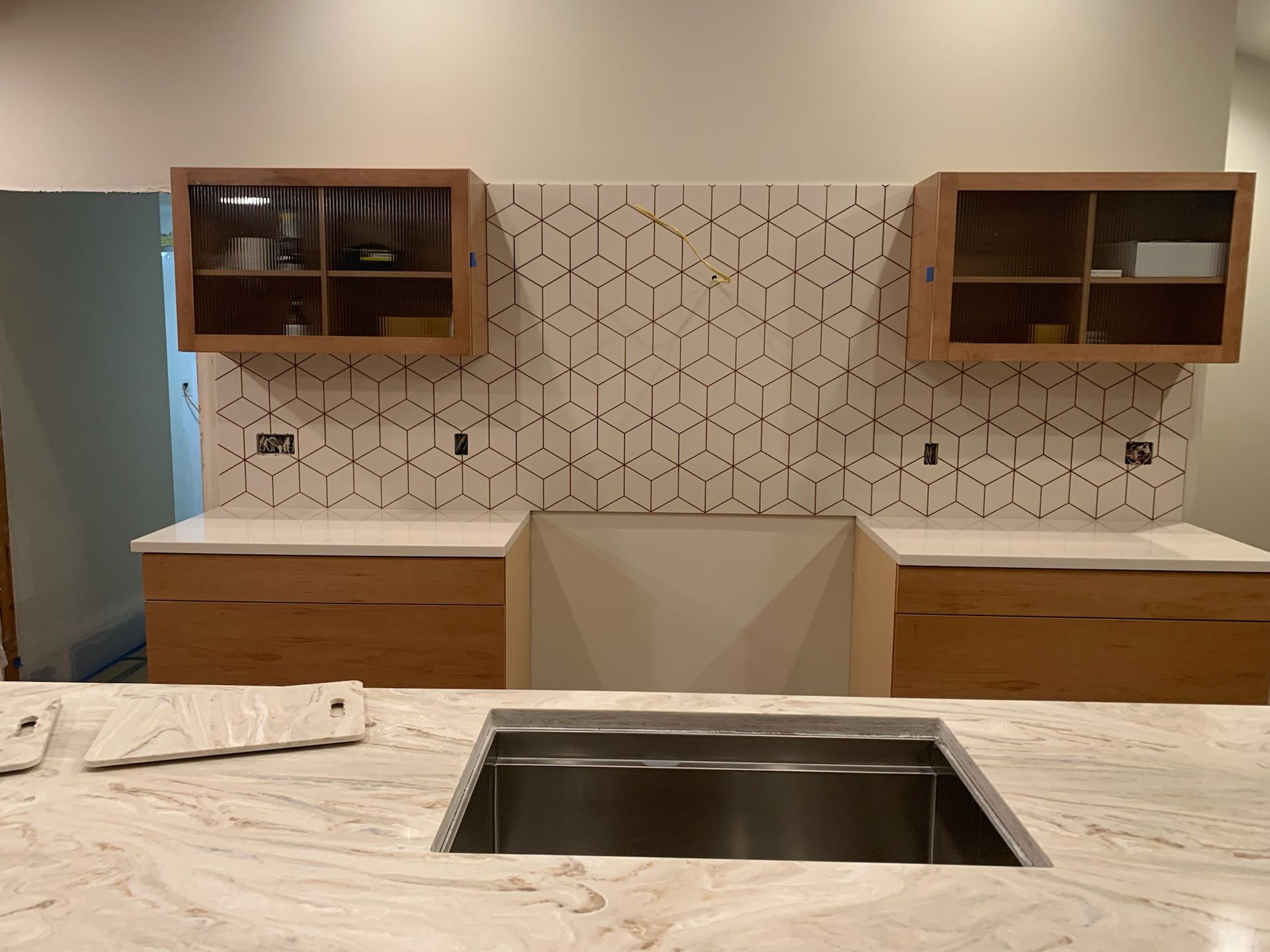 A kitchen with a stainless steel sink and a marble counter top.