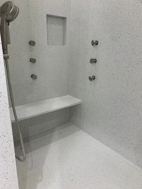There is a shower with a bench and a shower head.