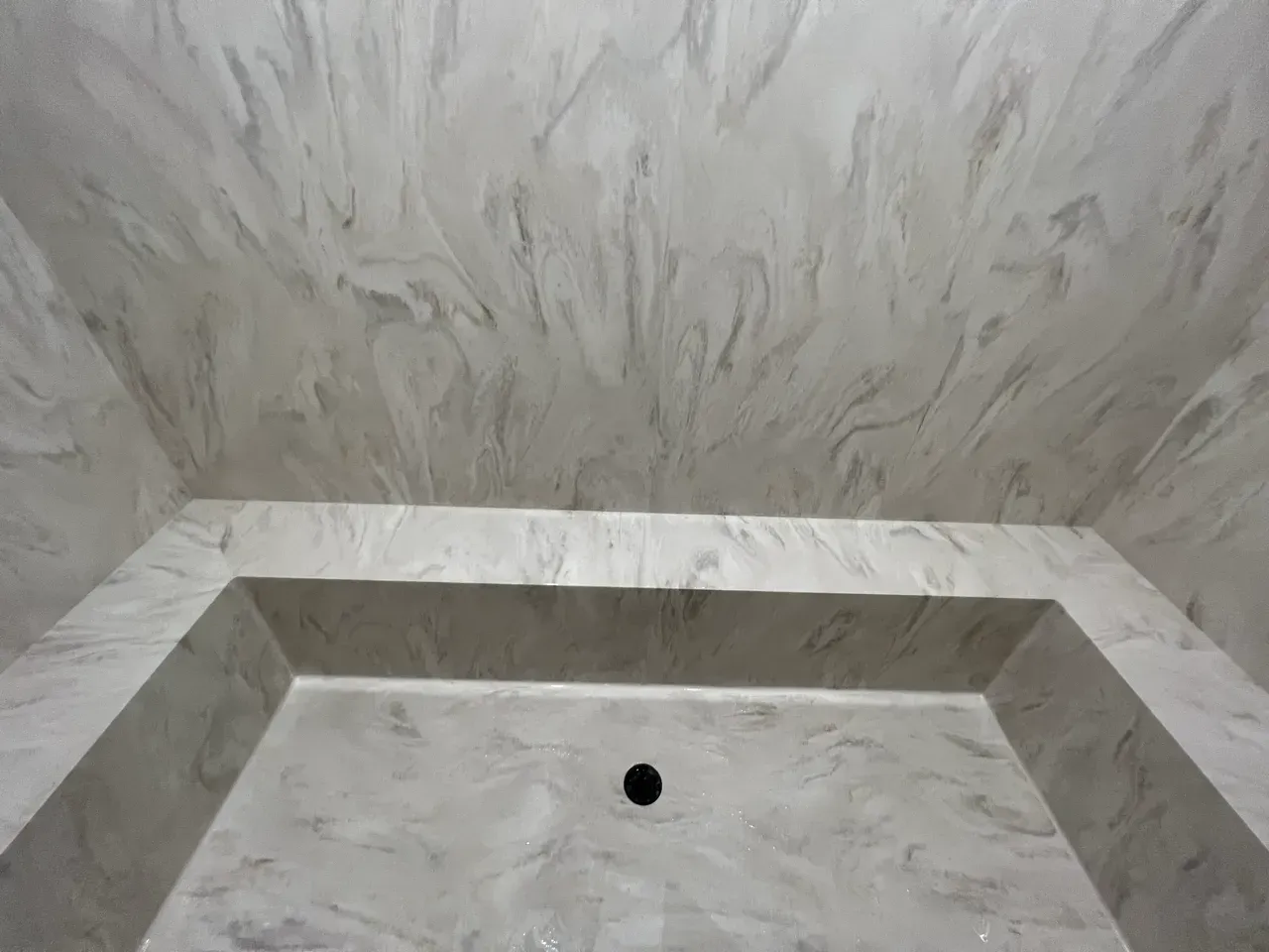 A bathroom with a marble shower stall and a marble ceiling.