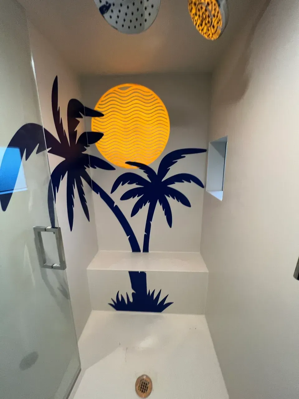 A bathroom with palm trees and a sun painted on the wall
