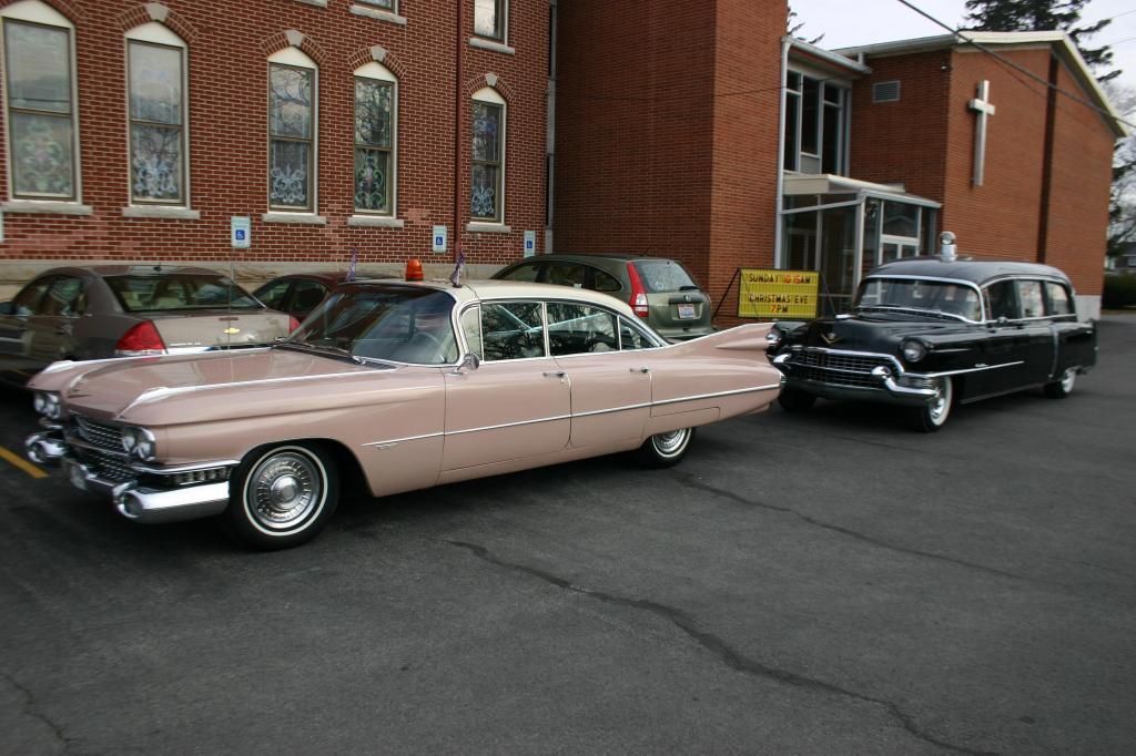 a pink car is parked next to a black car in front of a church