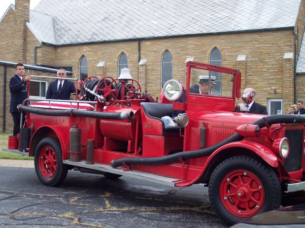 a red fire truck with a hose attached to it is parked in front of a church