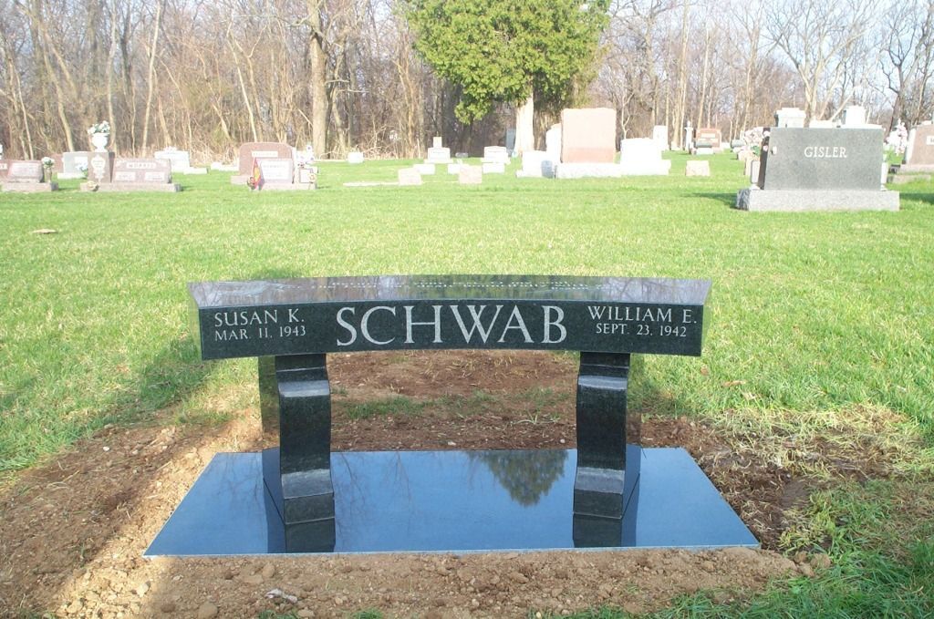 a black bench in a cemetery with the name schwan on it