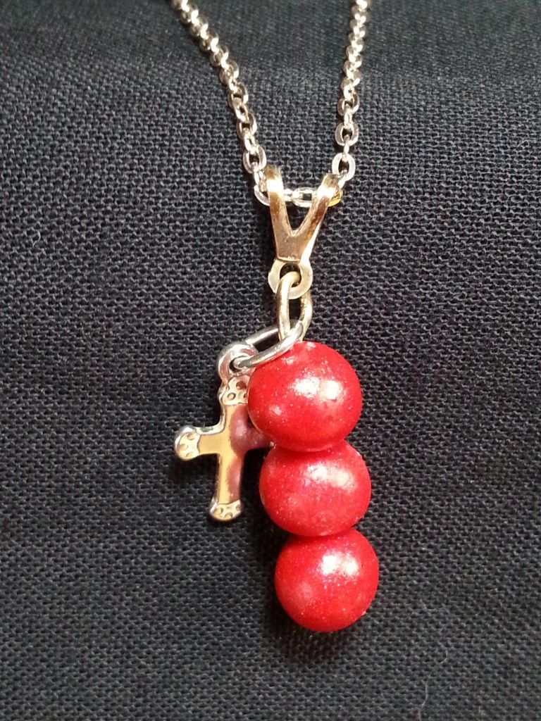 a necklace with three red beads and a cross