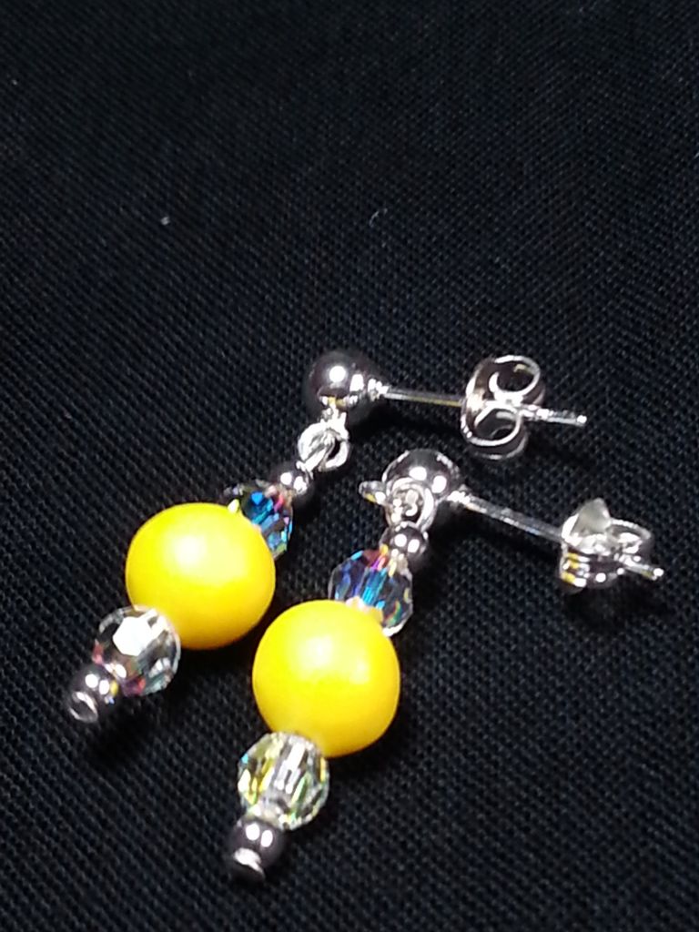 a pair of earrings with yellow beads and crystals